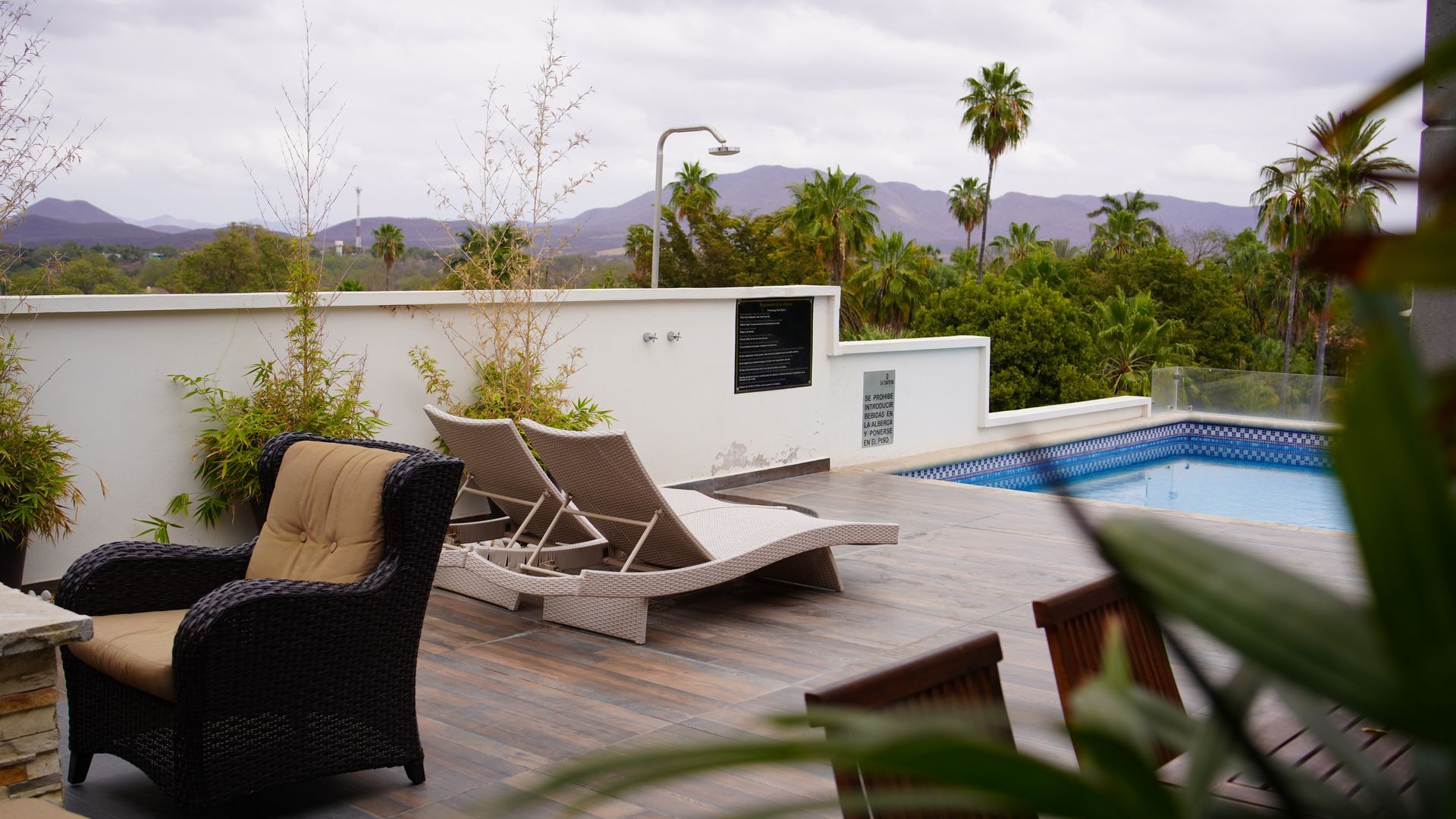 Un patio con sillas y una piscina al fondo.