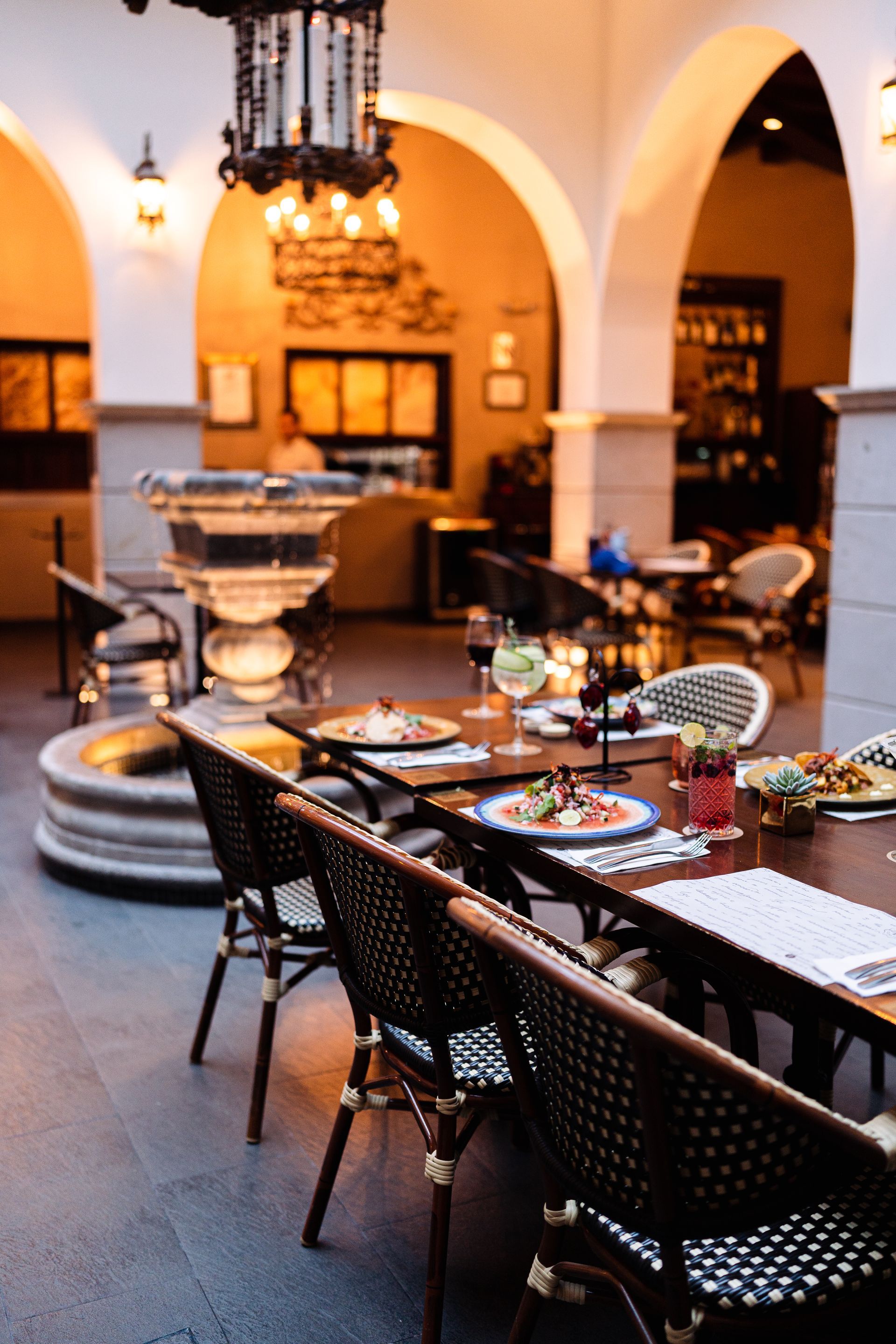 A restaurant with tables and chairs and a fountain in the middle