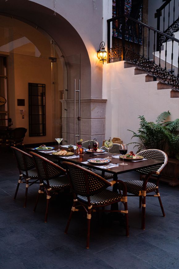 Una mesa larga con sillas y platos sobre ella.
