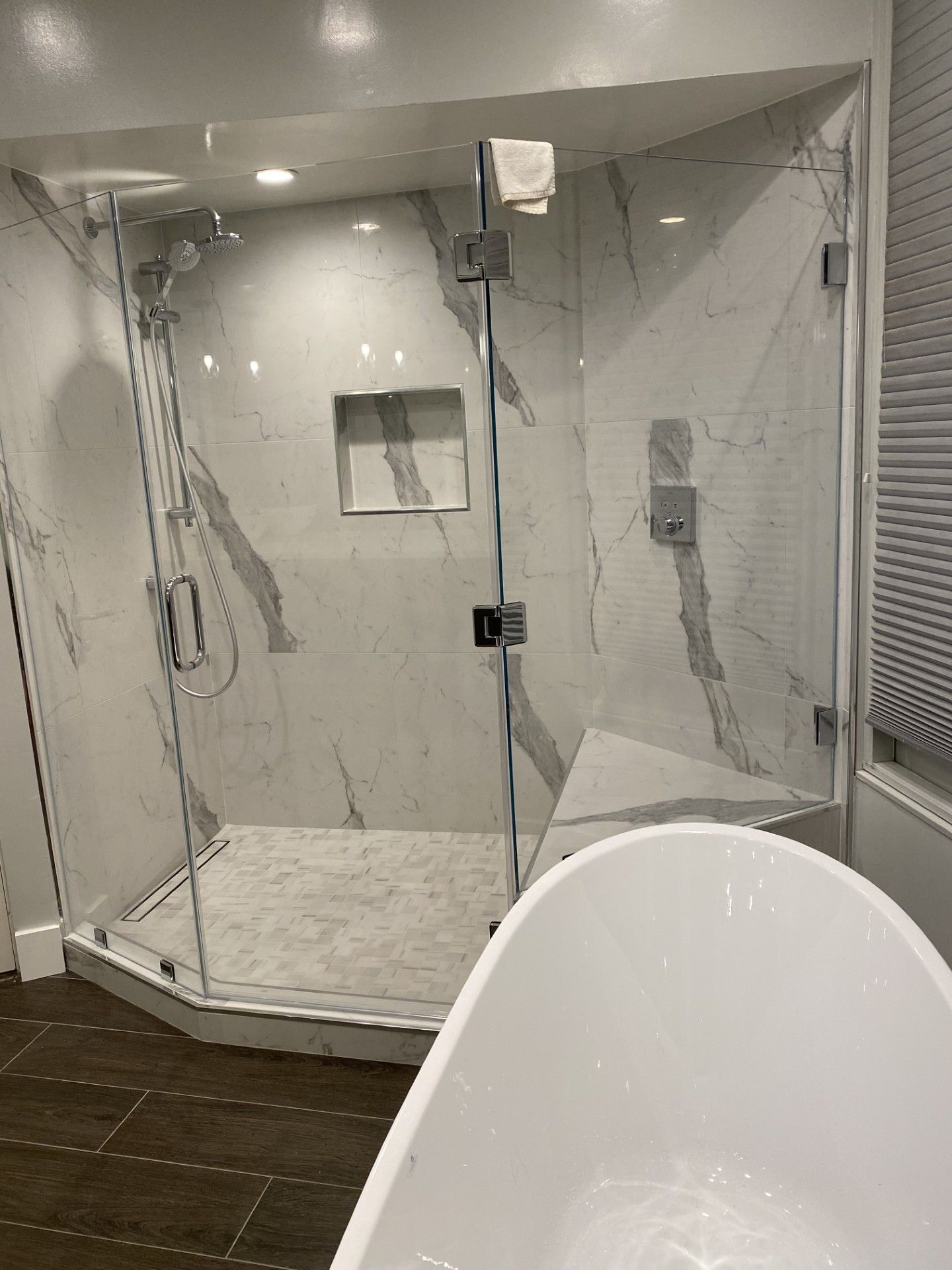 Custom tiled shower with built-in niche and glass door
