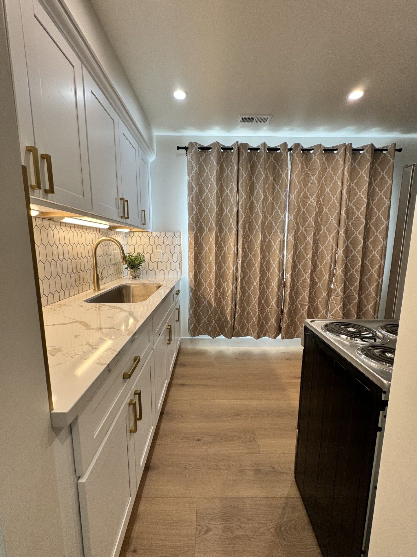 White kitchen cabinets, a sink, and curtains
