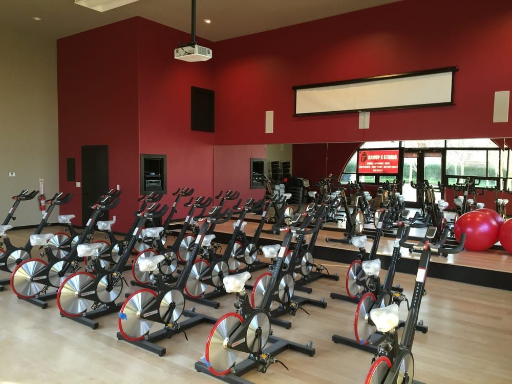 A row of exercise bikes are lined up in a gym.