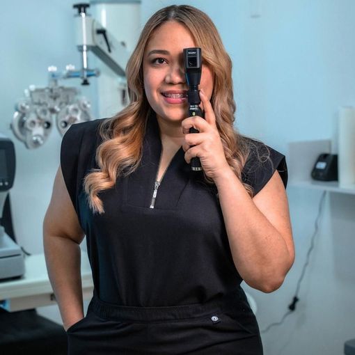 Una persona en una clínica sostiene un dispositivo médico portátil y sonríe frente a un equipo de diagnóstico.