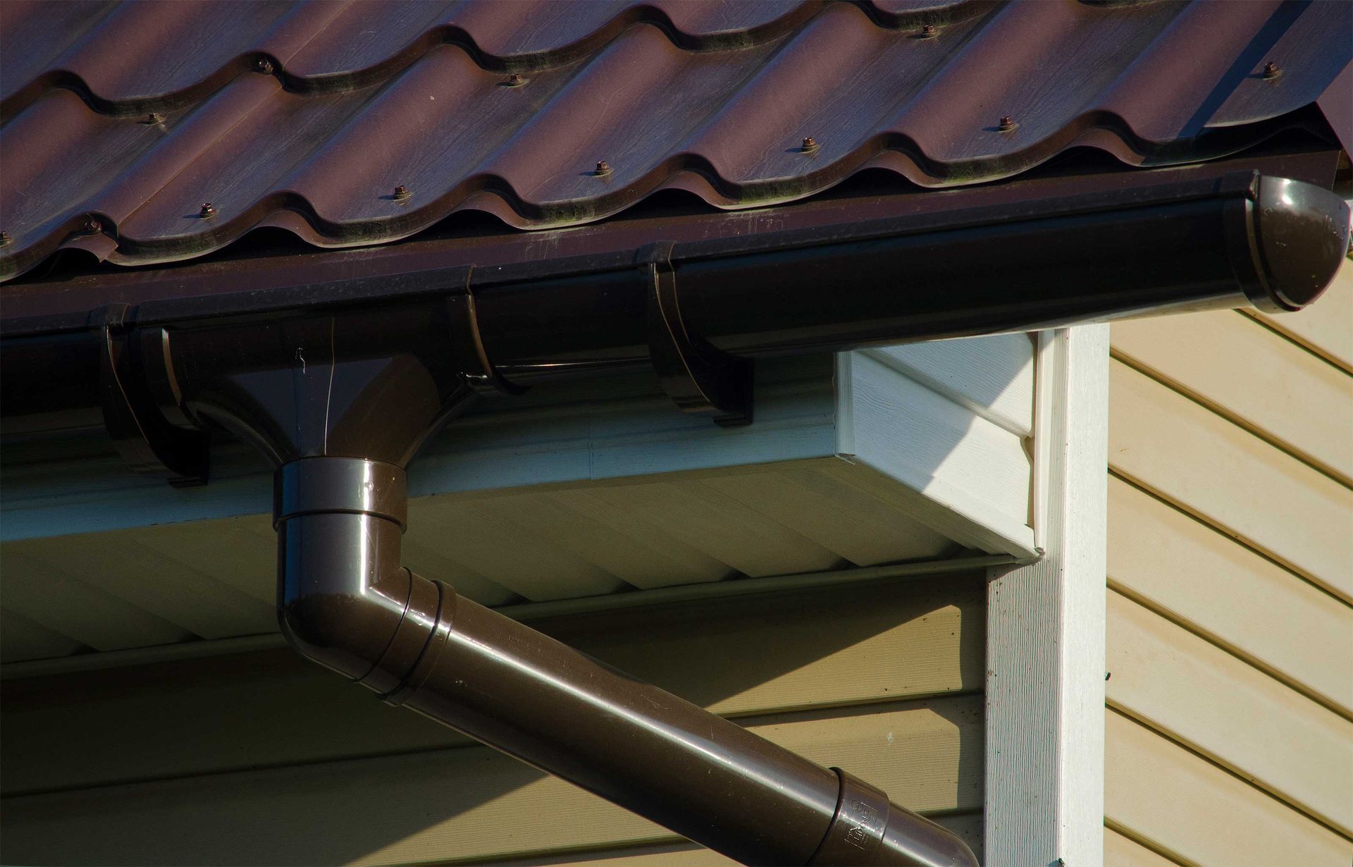 A close up of a brown gutter on the side of a house.