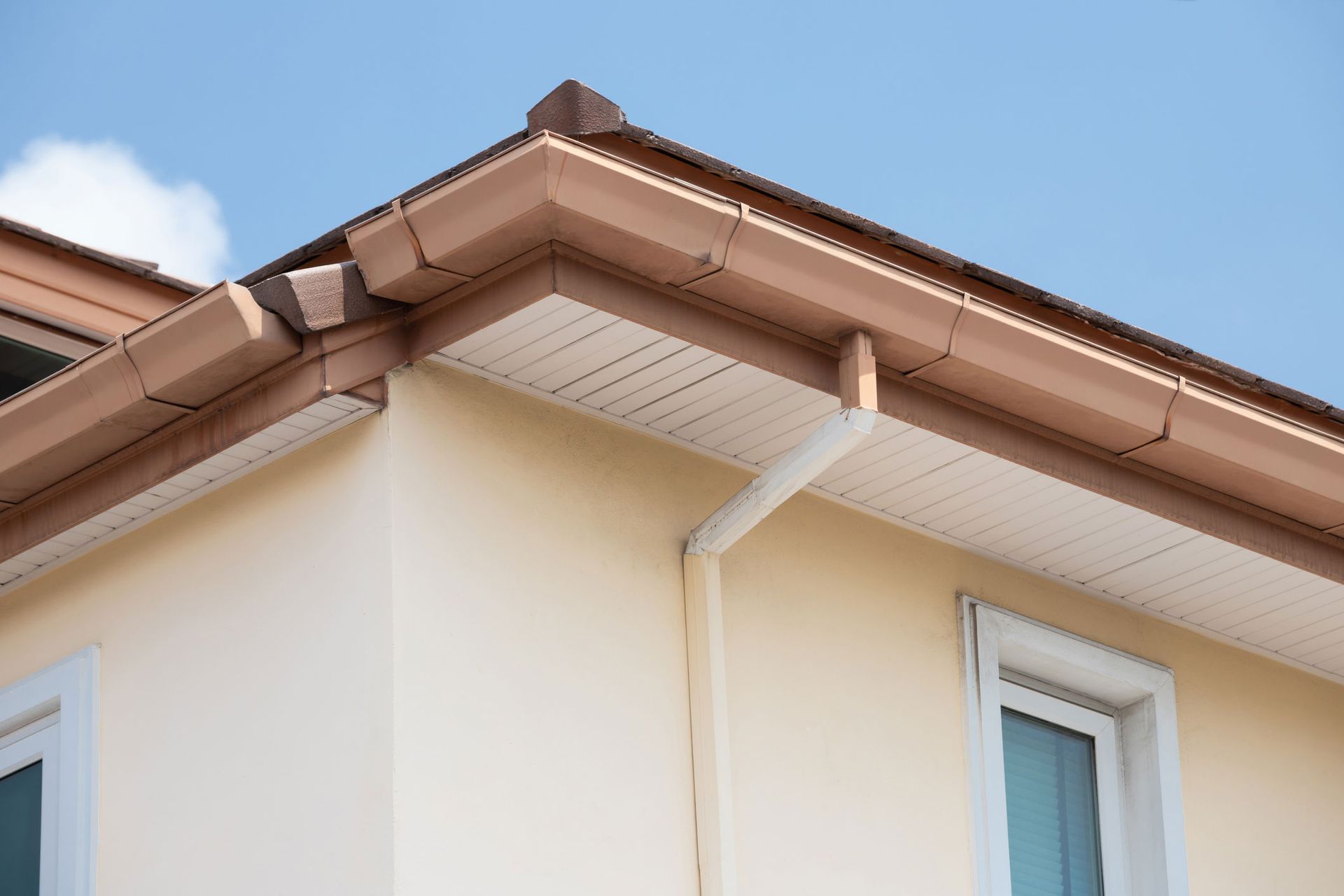 A close up of the roof of a house with a gutter and a window.