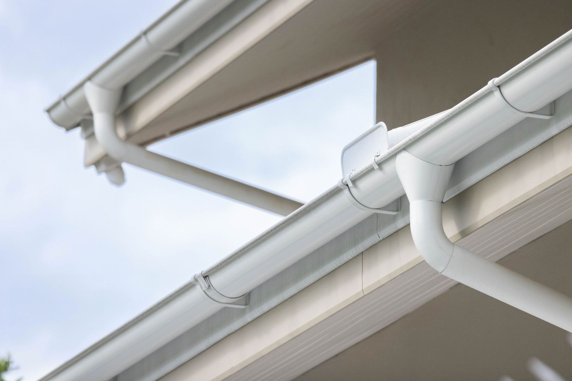 A close up of a white gutter on the roof of a house.
