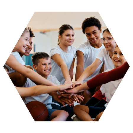 Group of smiling kids stacking hands in a team huddle, showing teamwork, unity, and positive community spirit