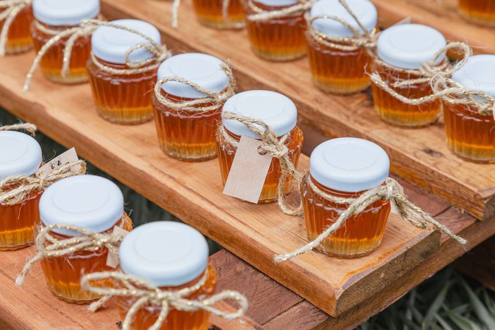 A row of small jars of honey on a wooden tray.