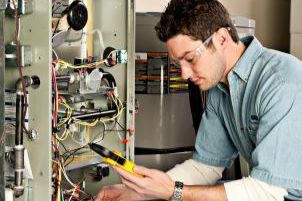 Technician using a multimeter to inspect exposed electrical wiring in a service panel