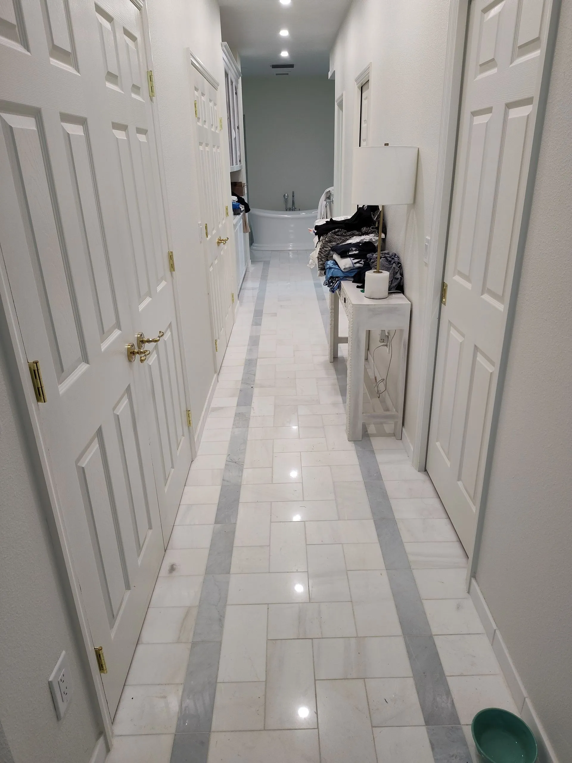 Narrow white hallway with closet doors and clutter on the floor