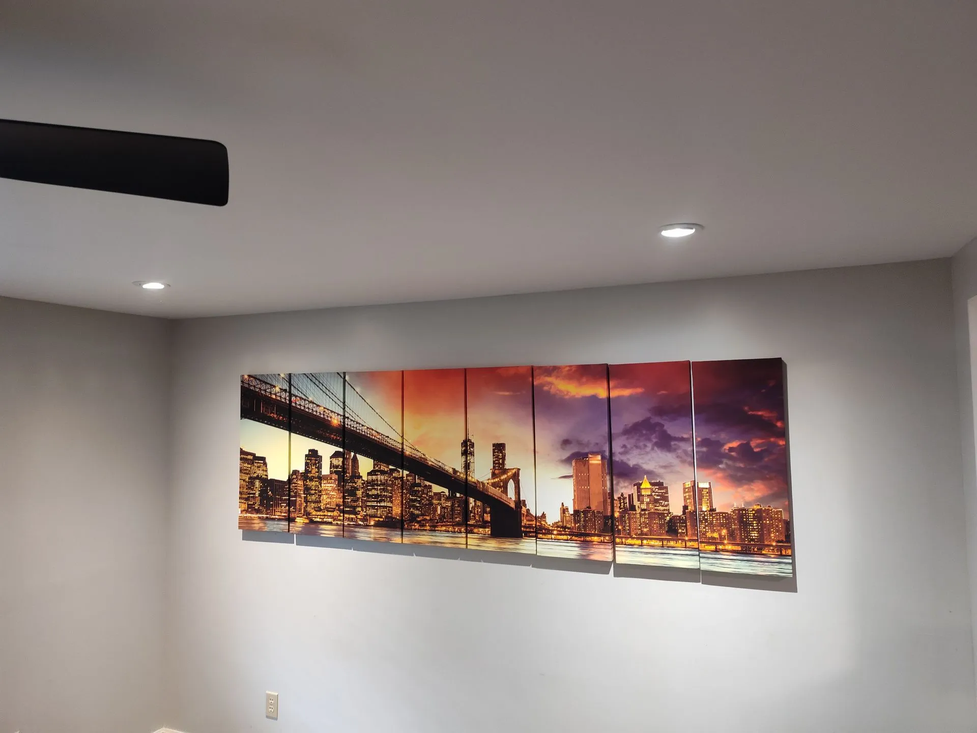 Framed sunset cityscape artwork on a light gray wall in a modern room.