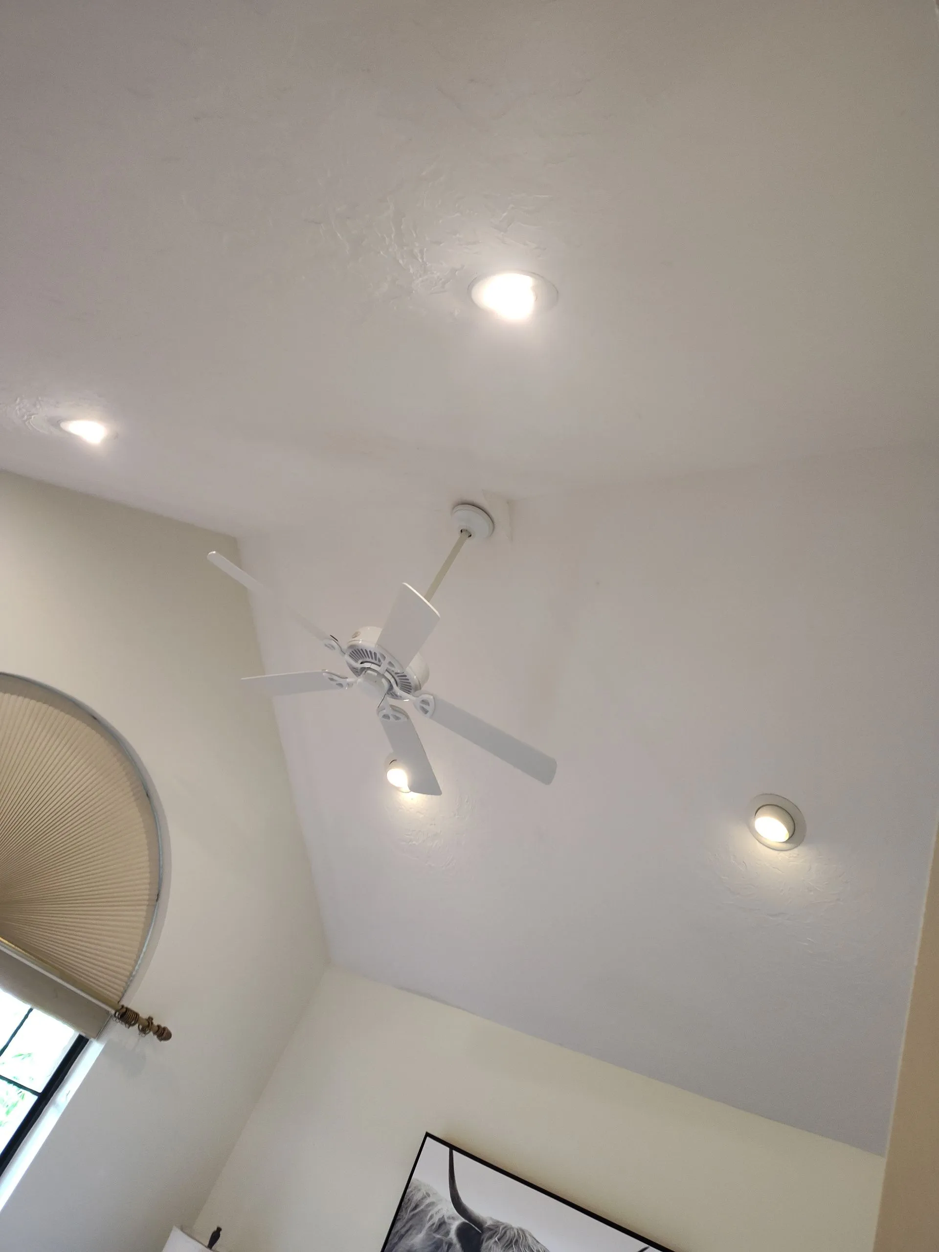 Ceiling with a white fan and recessed lights in a bright room