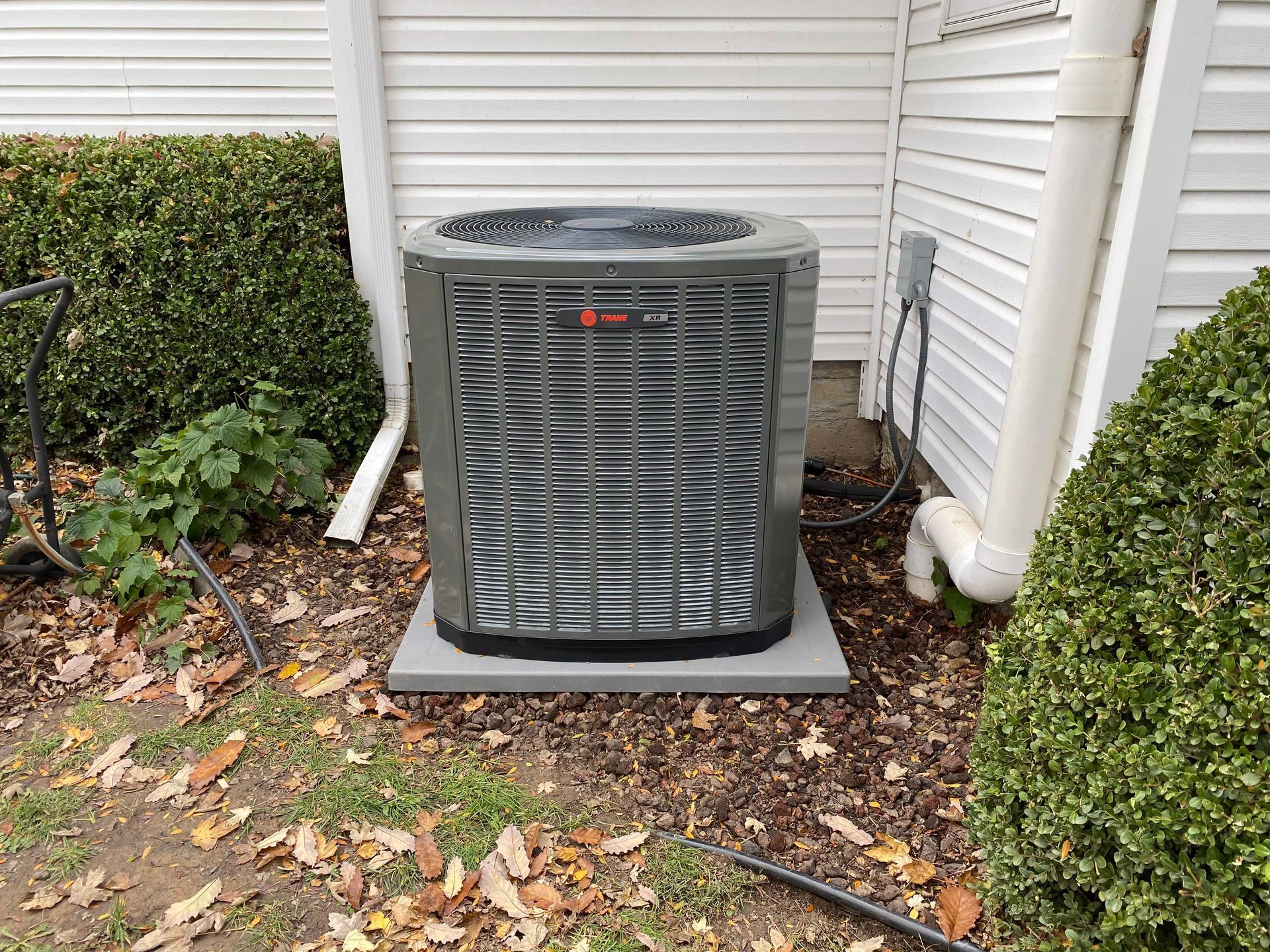 A large air conditioner is sitting on the side of a house.
