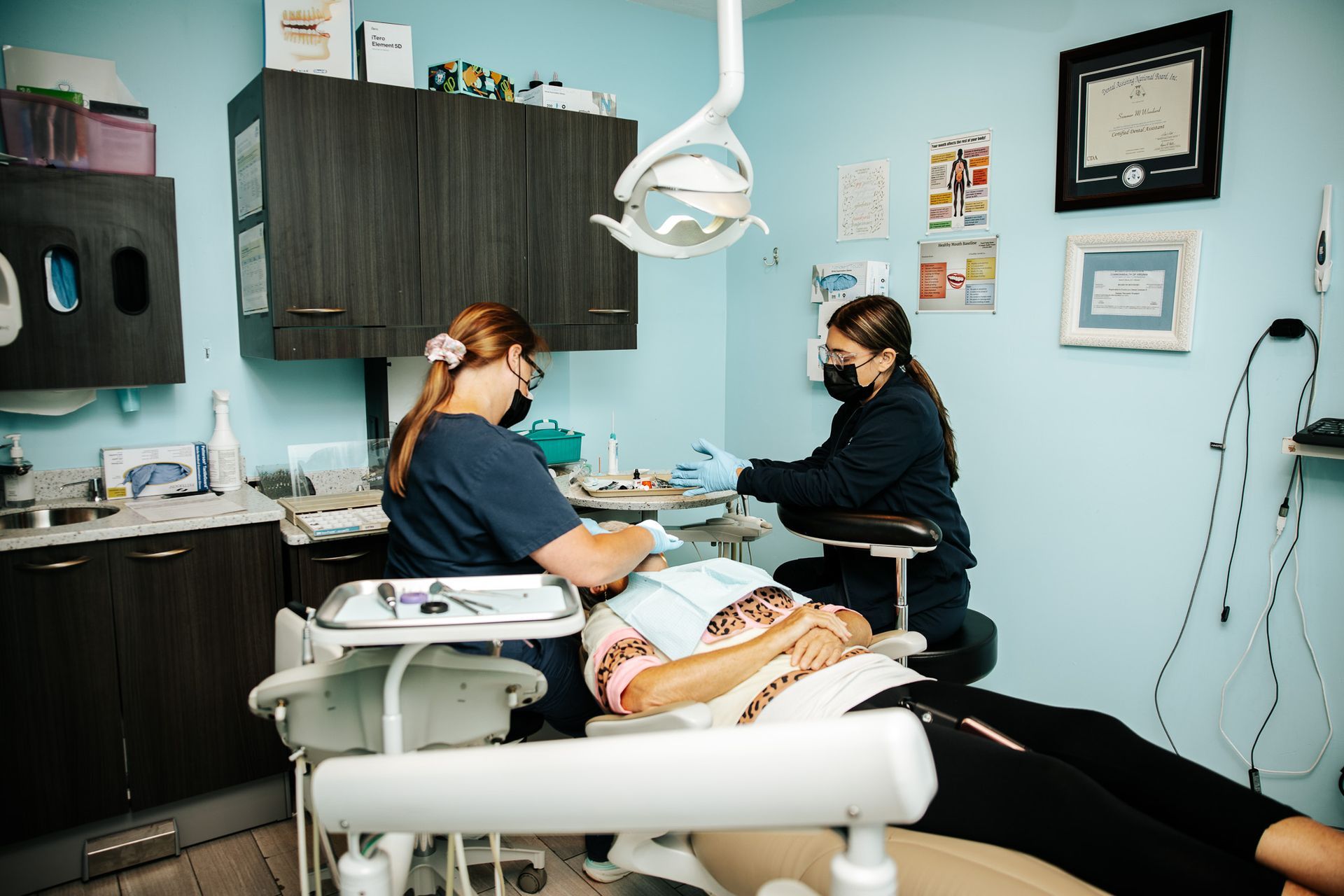 Two dental professionals providing care to a patient in a dentist's office.
