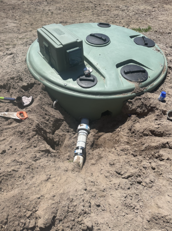 A Green Septic Tank is Sitting in the Middle of a Dirt Field — Plumbtek Solutions In Mudgeeraba, QLD