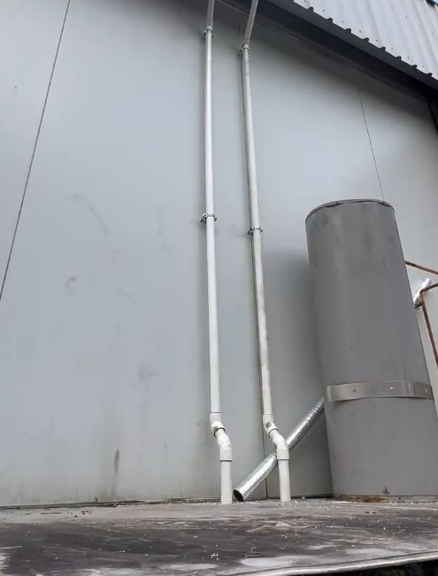 Two White Pipes Are Attached to the Side of a Building — Plumbtek Solutions In Mudgeeraba, QLD