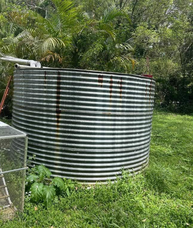 A Large Metal Tank is Sitting in the Middle of a Grassy Field — Plumbtek Solutions In Nerang, QLD