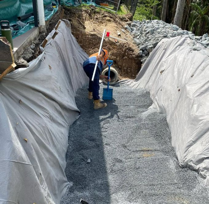 A Man is Digging a Hole in the Ground With a Shovel — Plumbtek Solutions In Currumbin, QLD