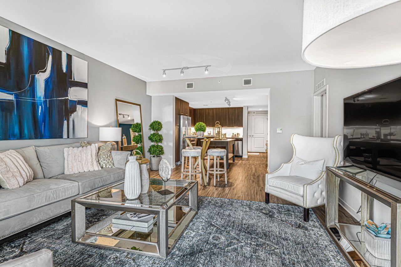 Open-concept living room with gray sofa, glass coffee table, and kitchen island.