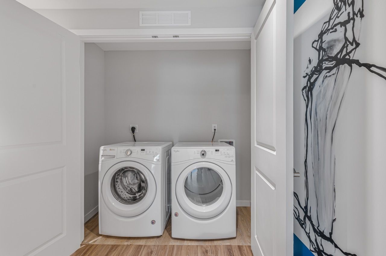 Laundry alcove with two front-loading washers and dryers in a small closet.