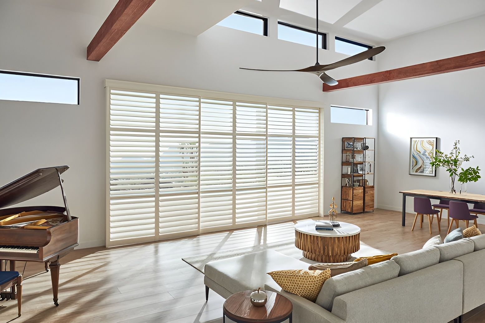 A living room with plantation shutters, piano and a couch.