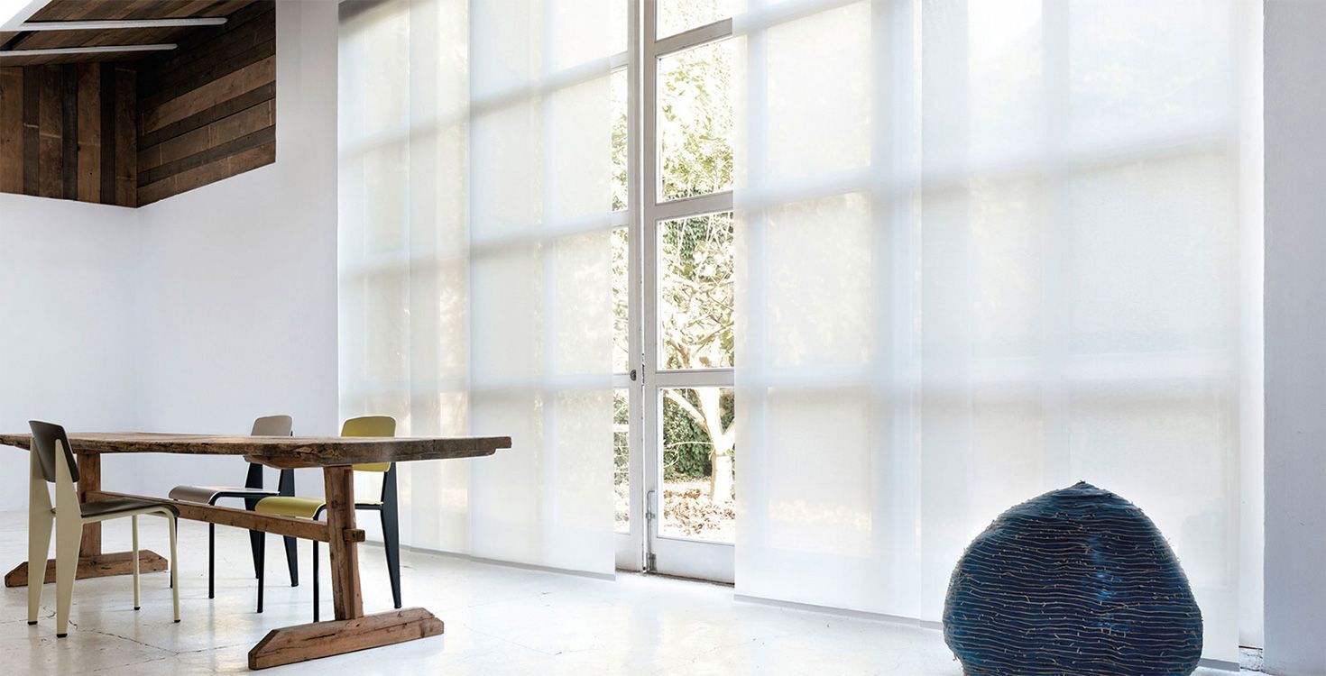 A dining room with a table and chairs and a large panel track window.