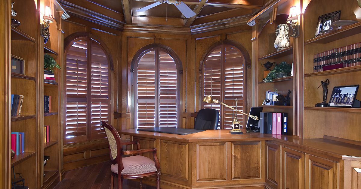Cozy home office featuring real wood shutters and a desk.
