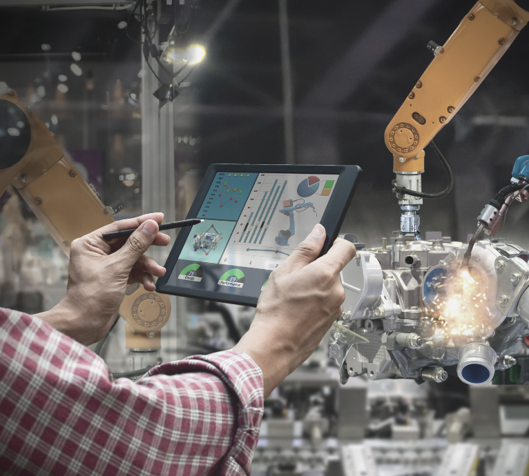 A man is holding a tablet in front of a robotic arm.