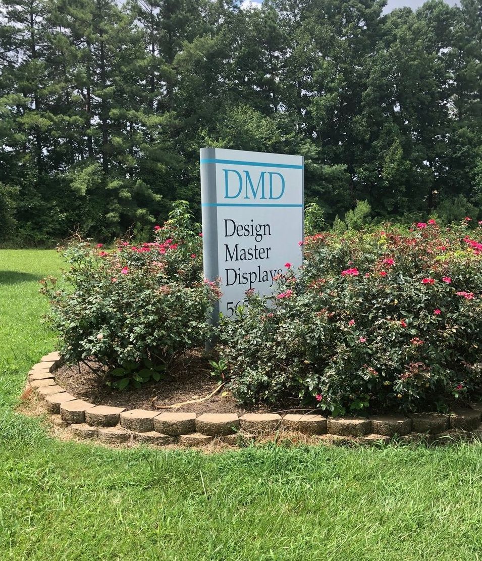 A sign for dmd is sitting in the middle of a lush green field.