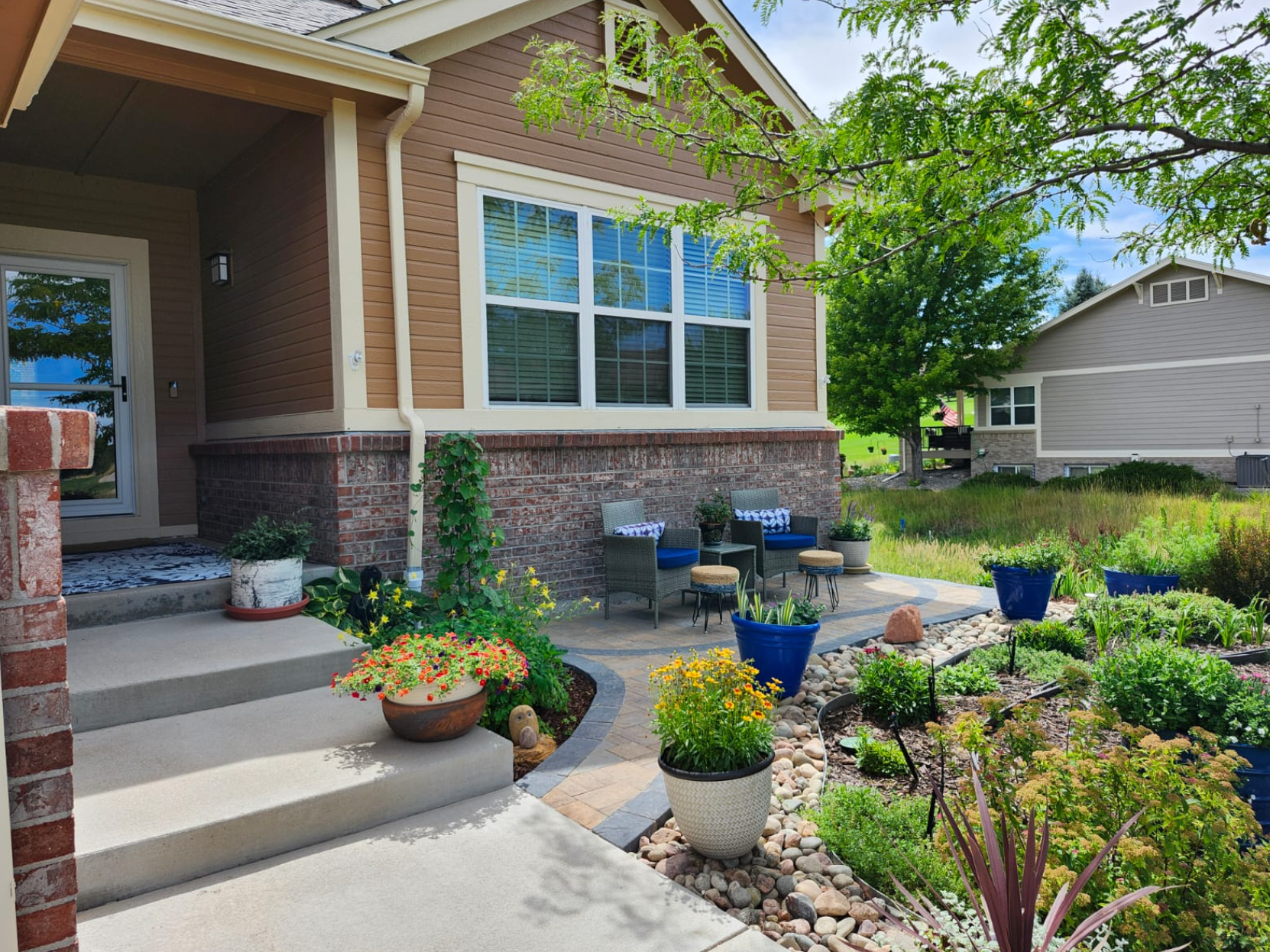 A house with a patio and potted plants in front of it.