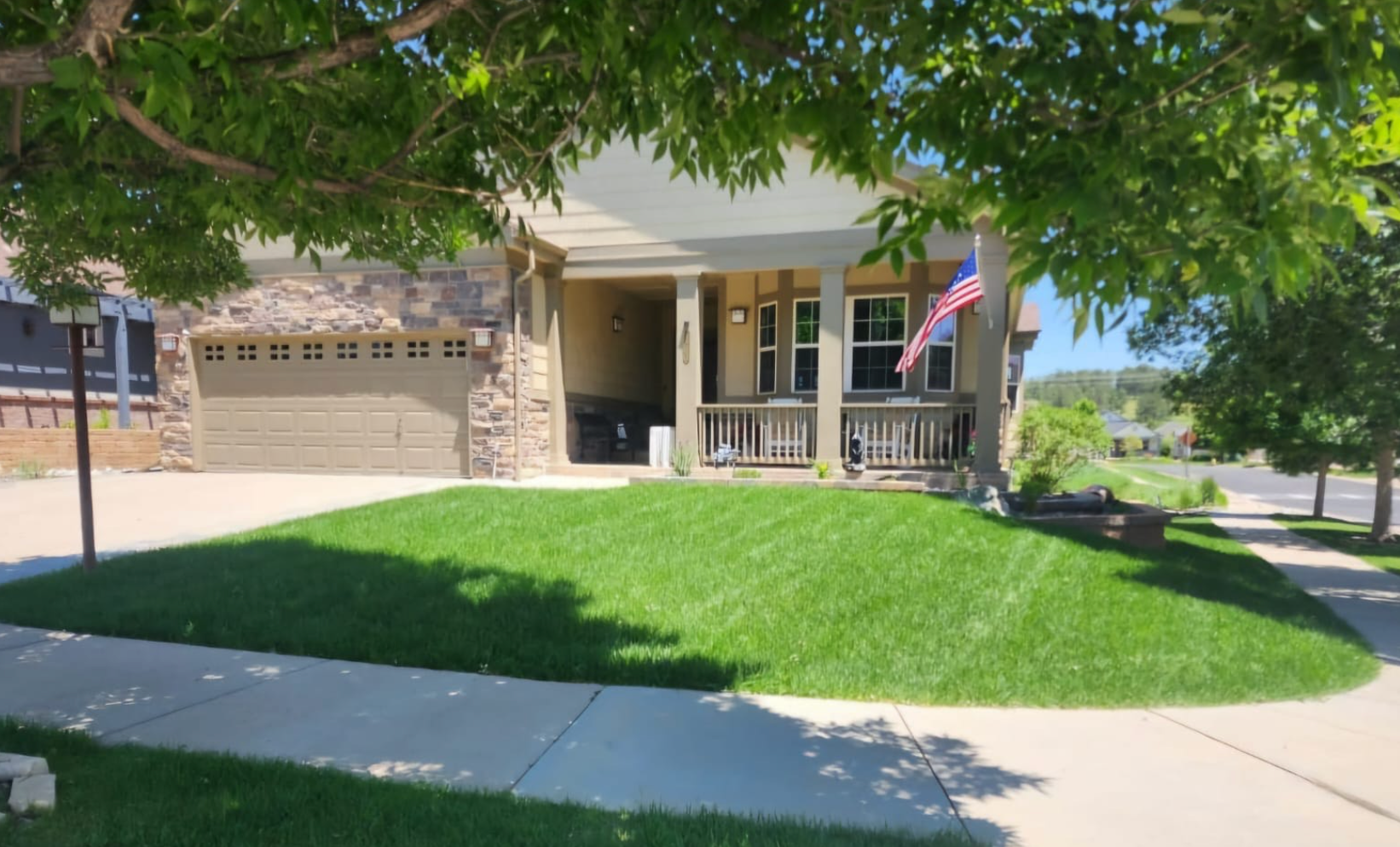 A house with a lush green lawn and a tree in front of it.
