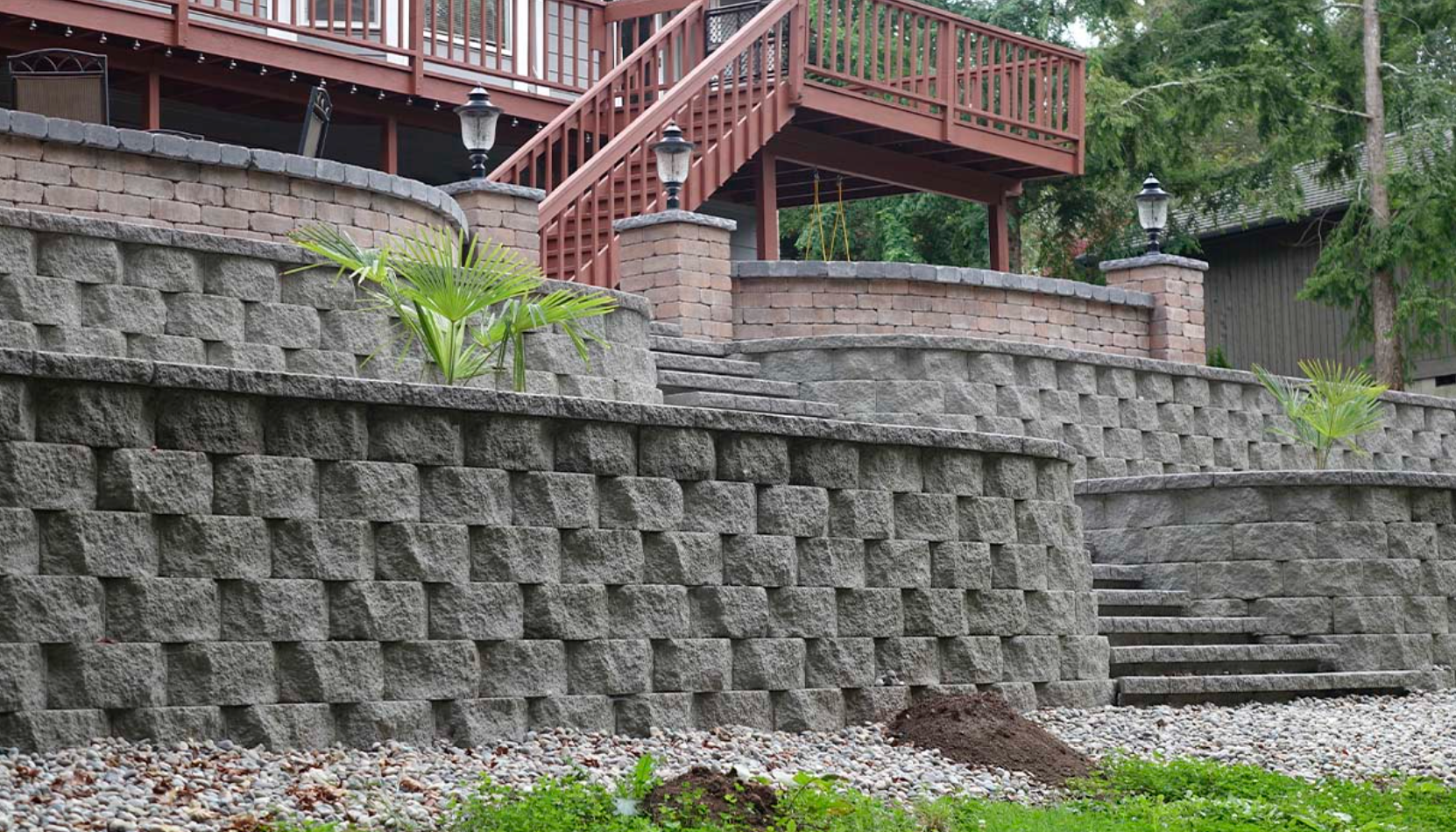 A large stone wall with stairs leading up to a house.
