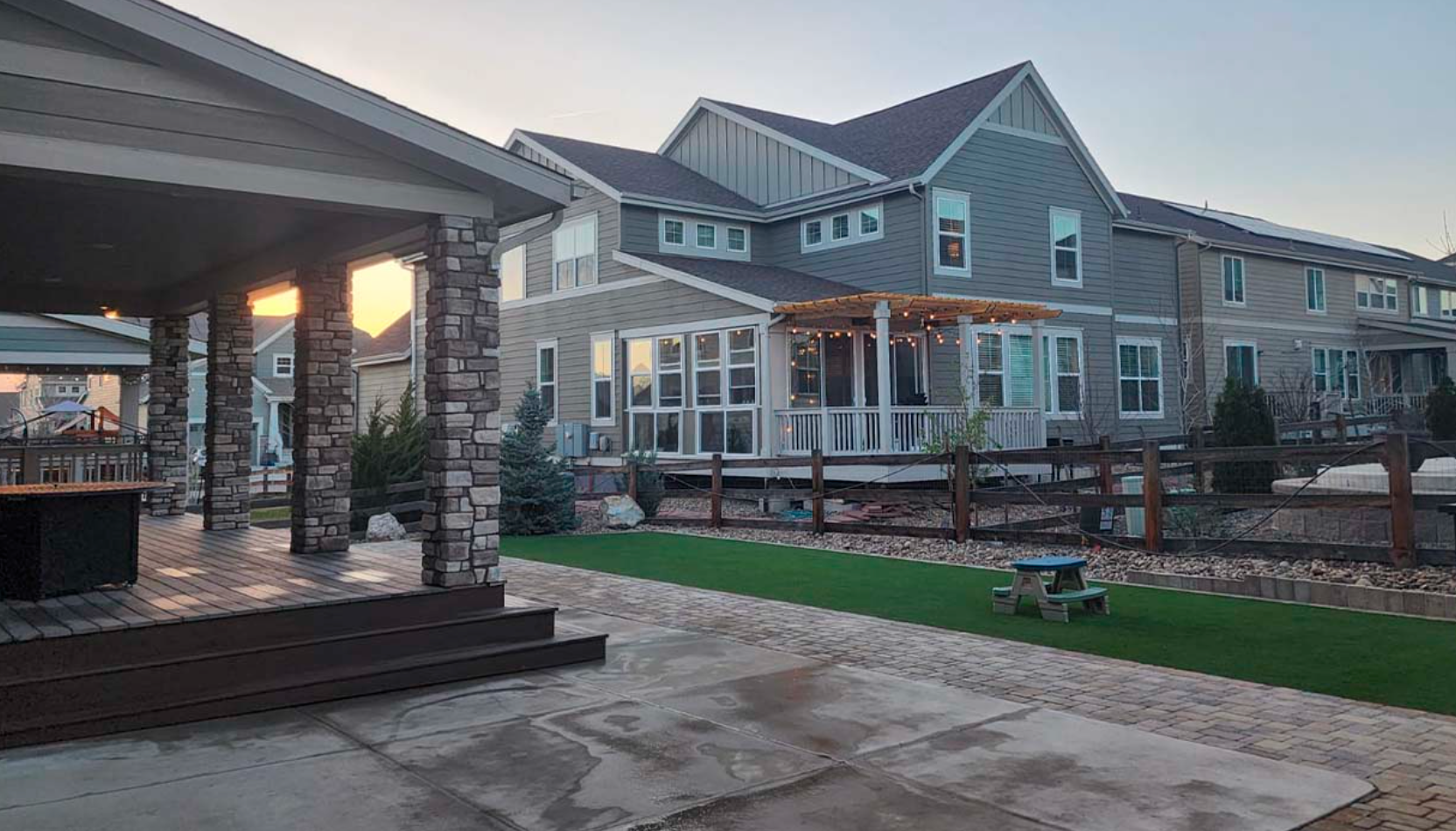 A large house with a porch and a picnic table in front of it.