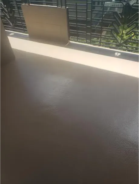 A window with a fence in the background and a shadow on the floor.