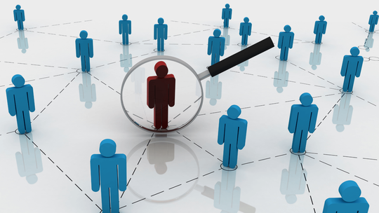Magnifying glass over a red figure, connected to blue figures, representing a network.