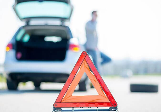 Un hombre está cambiando un neumático de un coche averiado.