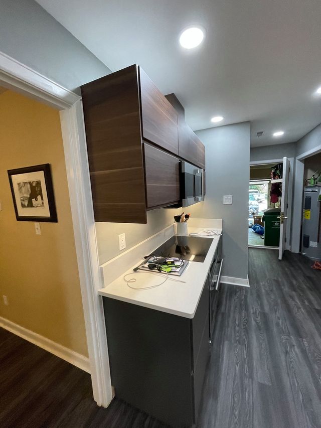 A kitchen with a stove , sink , cabinets and a picture on the wall.