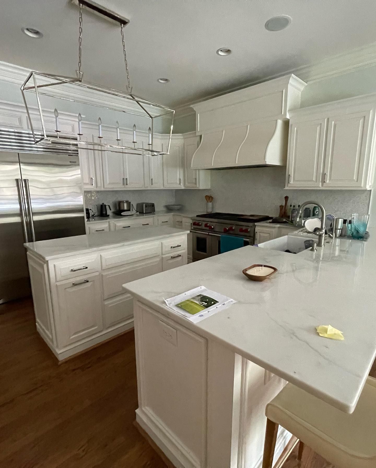 A kitchen with white cabinets , stainless steel appliances , and a large island.