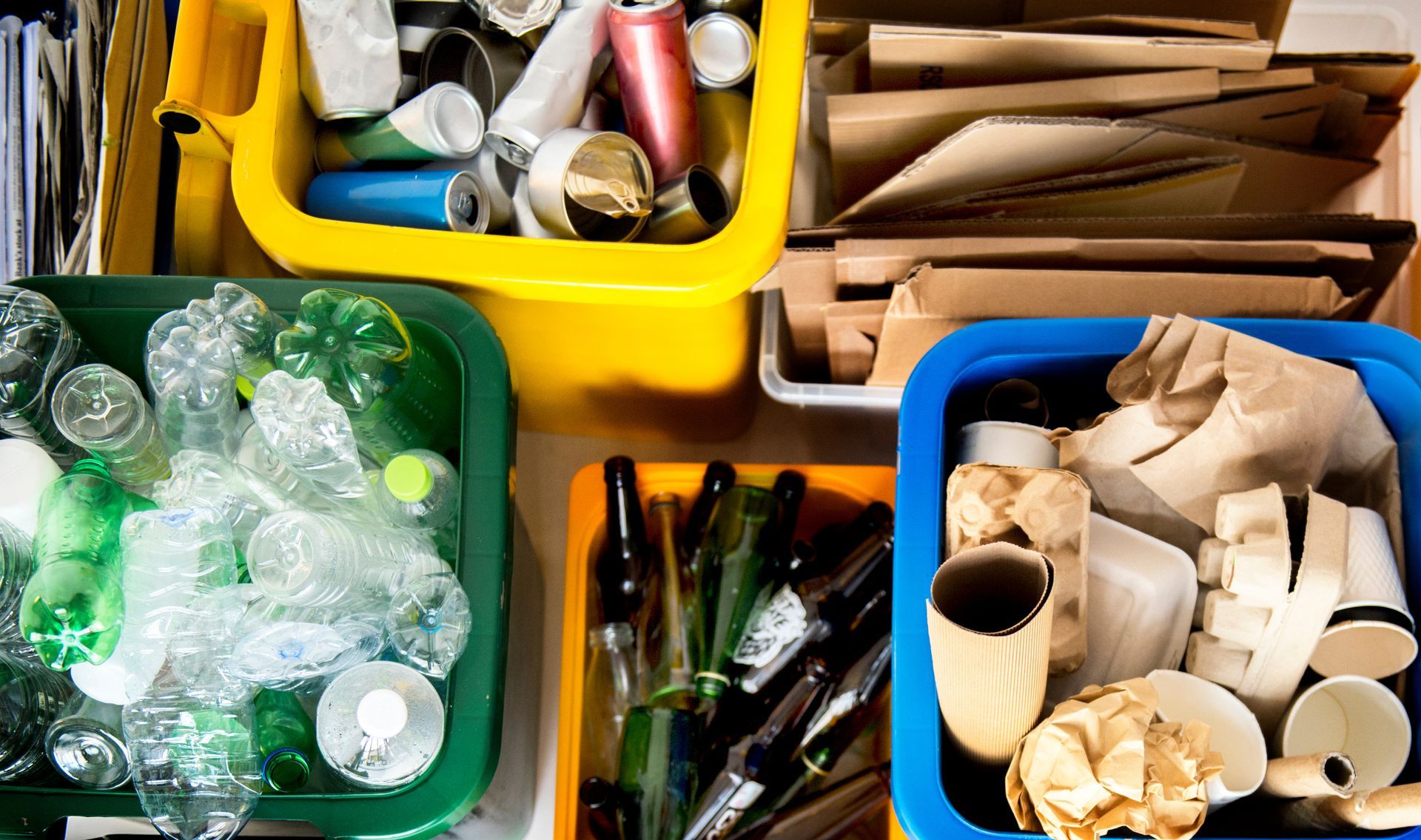 Top view of sorted glass, plastic, and metal bins ready for a local recycling pick up service.