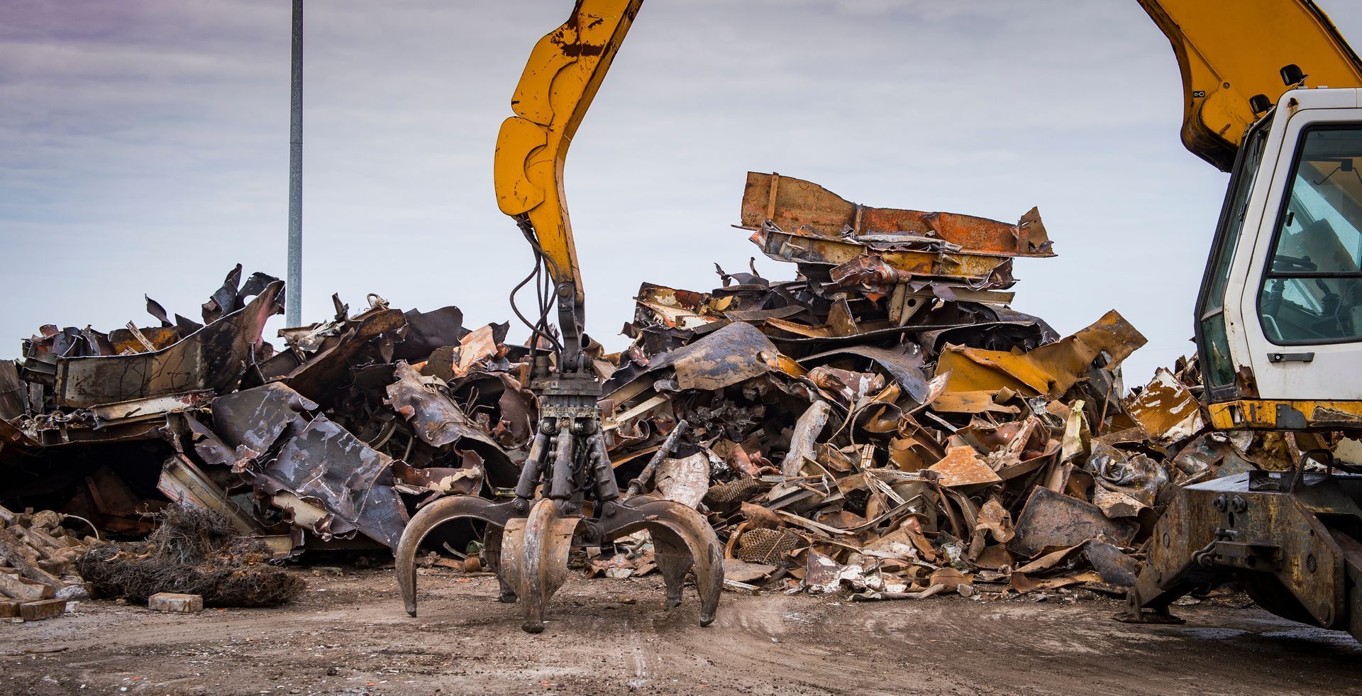 An industrial claw crane moving metal debris at a busy scrap metal recycling center for processing An industrial claw crane moving metal debris at a busy scrap metal recycling center for processing