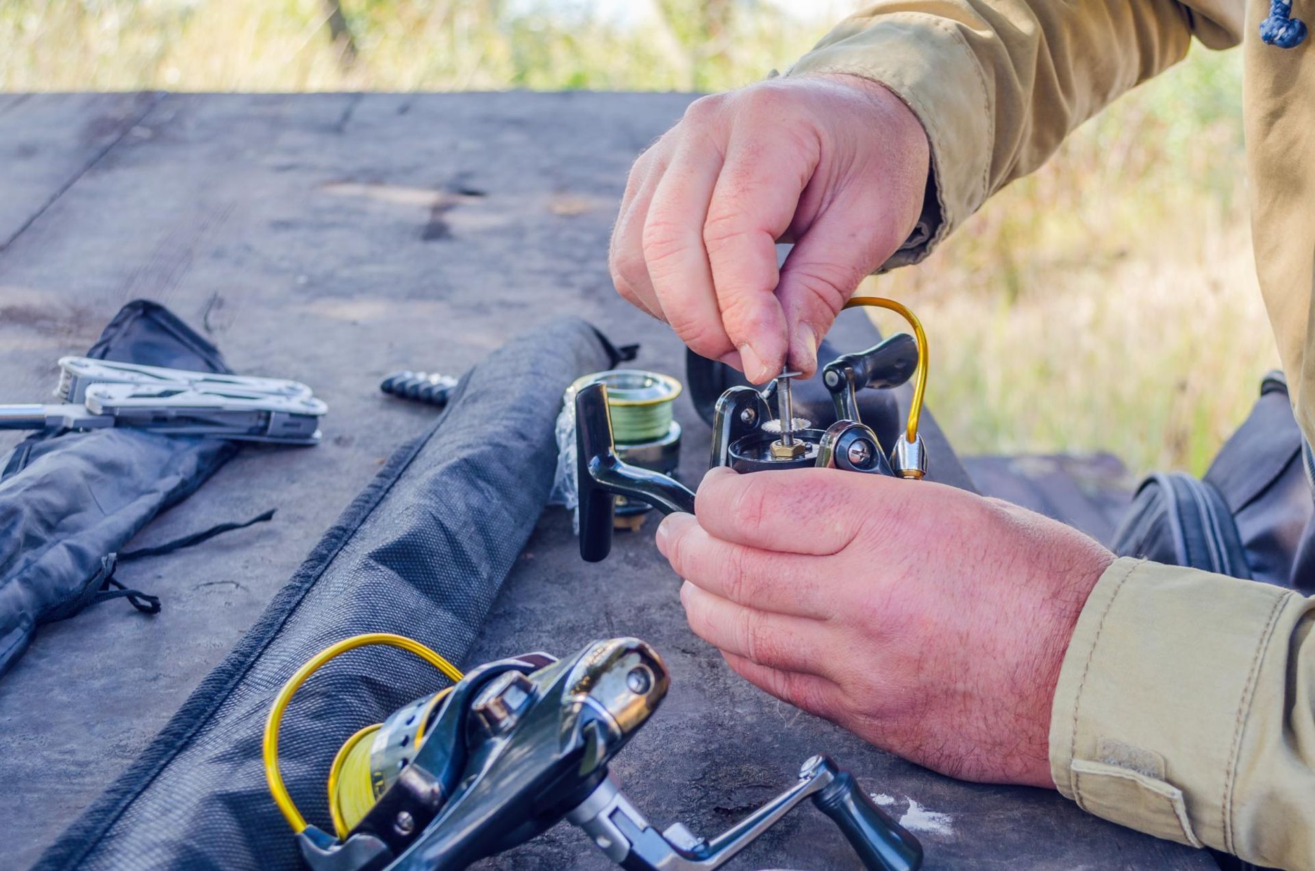 A man is fixing a fishing reel on a table.