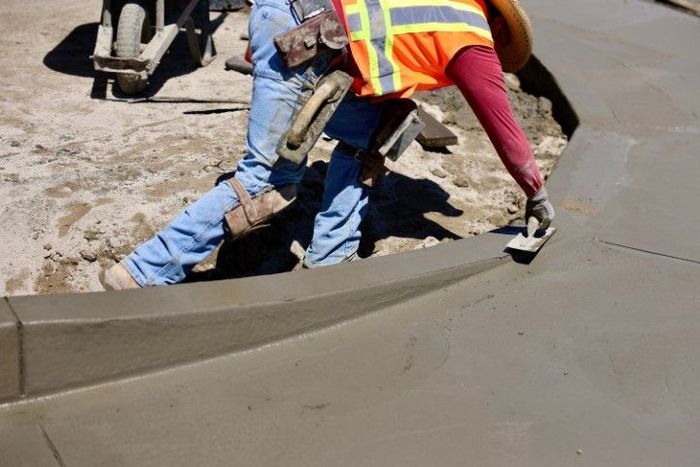 Concrete contractors shaping a concrete sidewalk. 