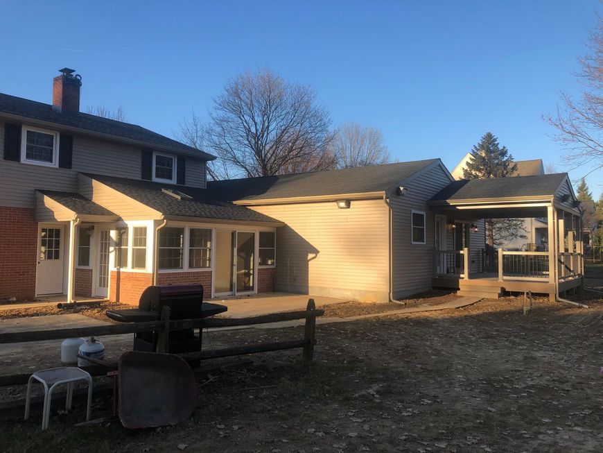 Backyard patio with a house, screened porch, and fire pit under a clear blue sky