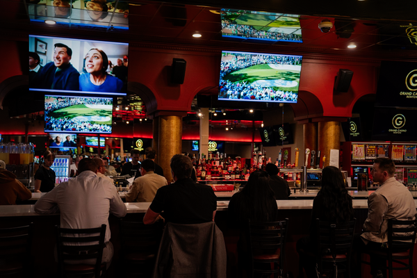Four people celebrating a win at a casino table covered in playing cards and stacks of colorful poker chips.