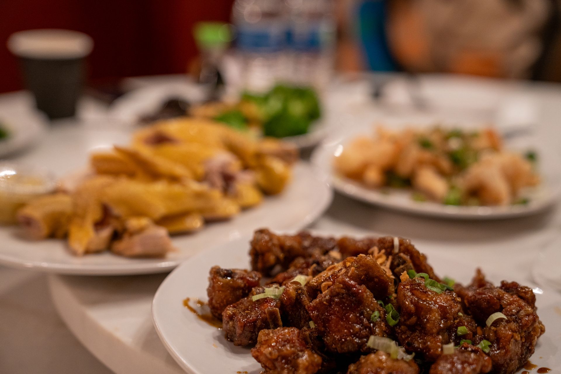 Multiple bowls of fried food topped with green onions and sauces arranged on a wooden table.