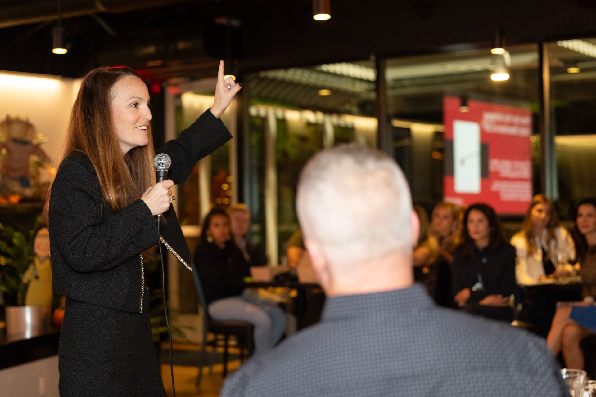 A woman is giving a presentation to a group of people while holding a microphone.