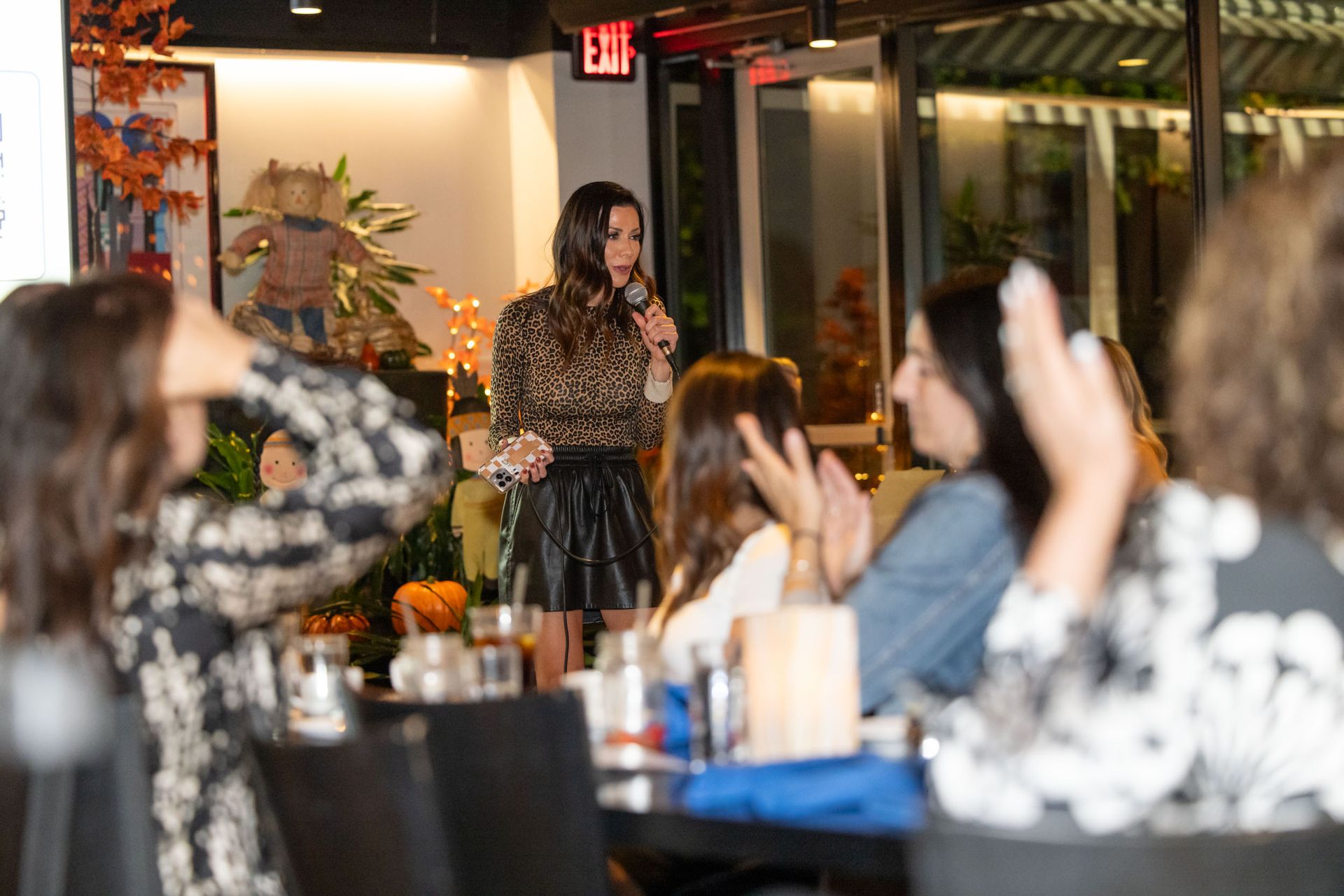 A woman is standing in front of a group of people holding a microphone.