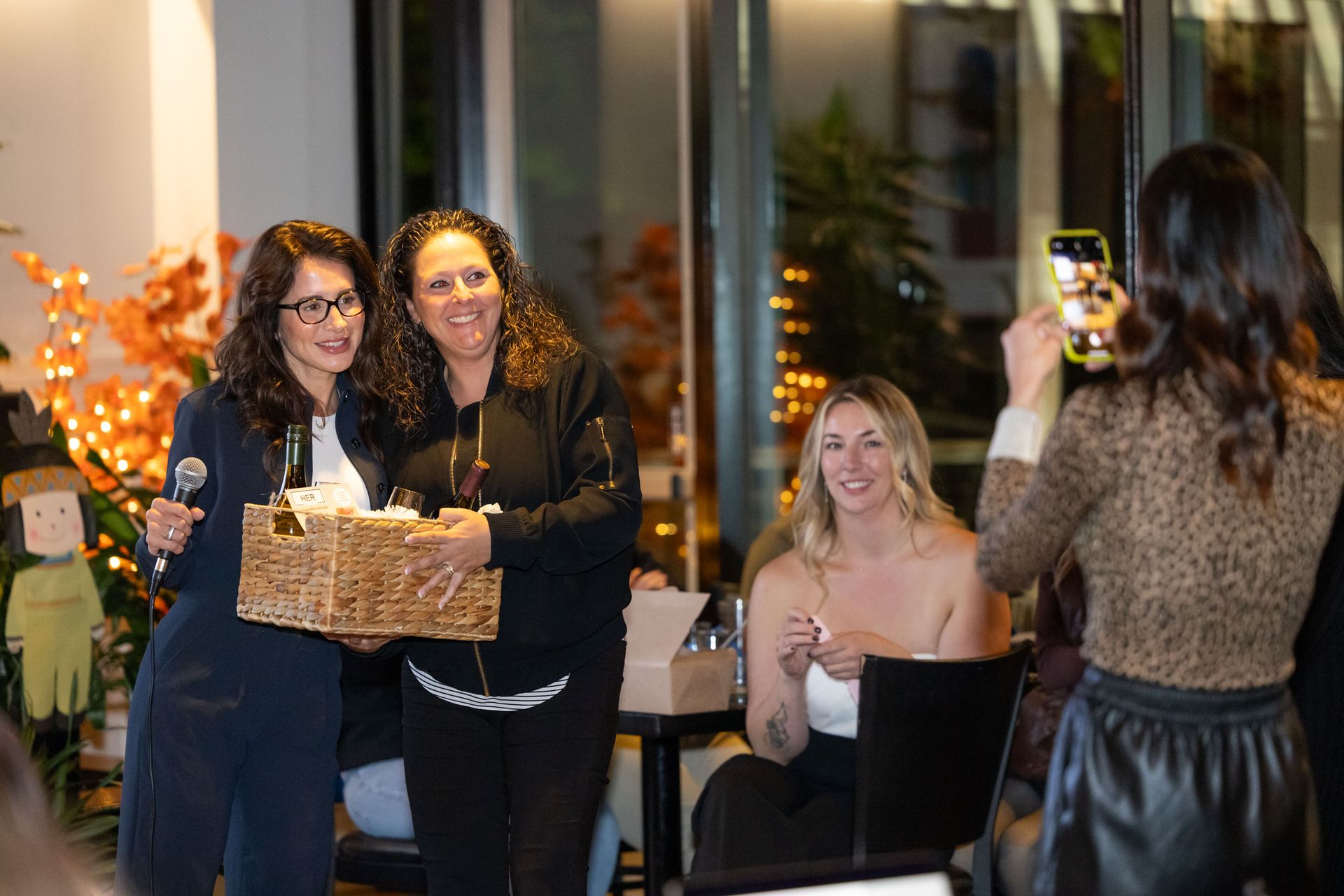 A woman is taking a picture of two women at a party.