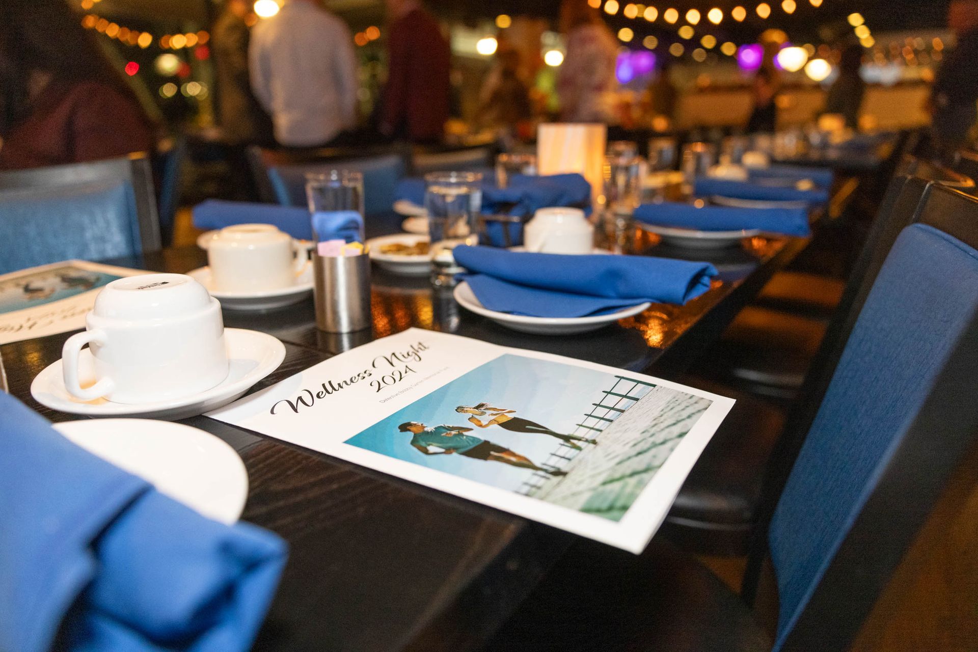 A restaurant table with plates , cups , napkins and a menu on it.