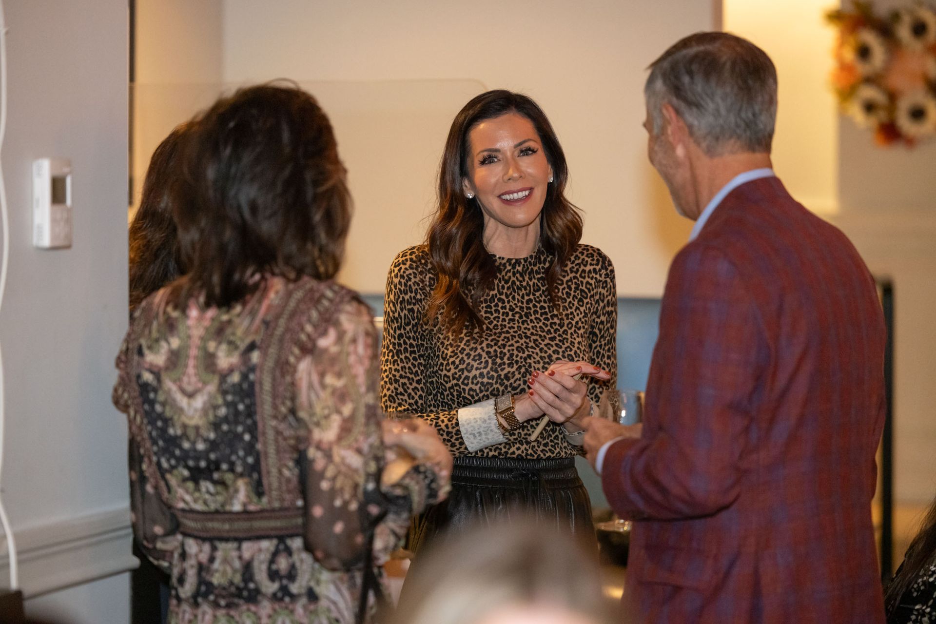 A group of people are standing around talking to each other in a room.
